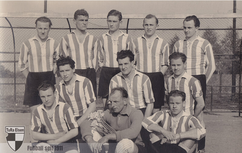 Schwarz-weiß Mannschaftsfoto der TuRa Elsen Fußballer in gestreiften Trikots, zweite Meisterschaft Bezirksliga 1956/57, Gruppenbild mit elf Spielern