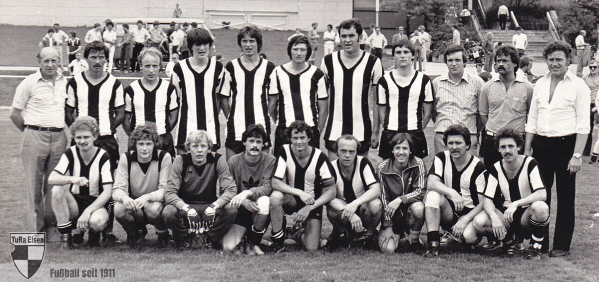 Schwarz-weiß-Foto der 2. Herrenmannschaft der TuRa Elsen von 1981, Spieler in gestreiften Trikots und Trainer auf einem Fußballfeld