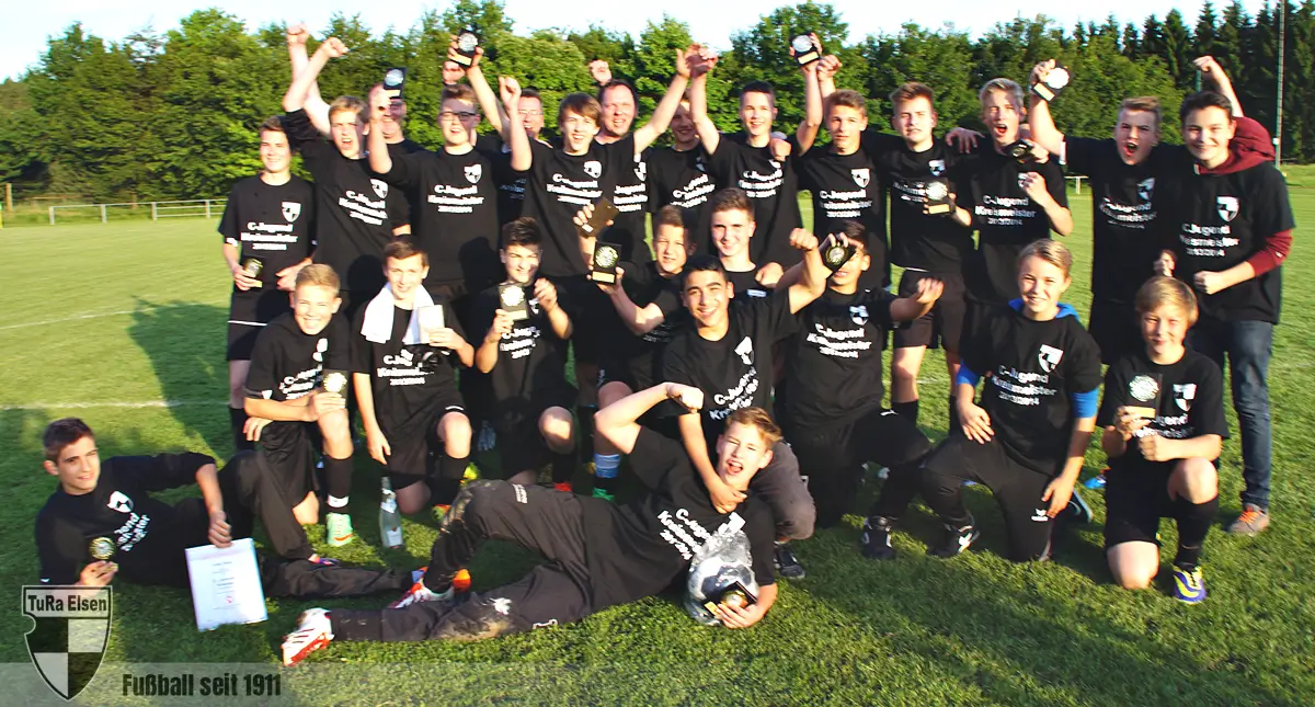 C-Junioren der TuRa Elsen feiern Kreismeisterschaft auf dem Spielfeld, tragen schwarze T-Shirts mit Aufdruck und halten Medaillen