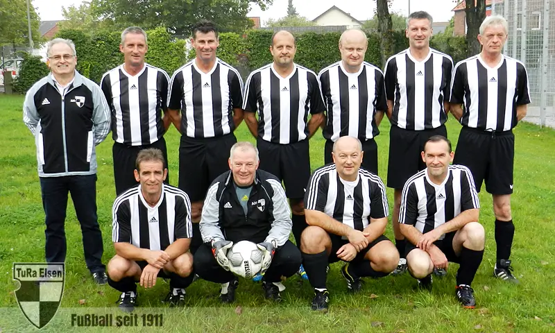 Das Team der TuRa | Hinten v. l.: Hans-Jürgen Duczek, Michael Daniels, Andreas Schröder, Dieter Gees, Ferdi Kniesburges, Walter Purschke und Robert Surmund; Vorne v. l.: Willi Kutowski, Helmut Hupe, Raimund Krick und Andreas Dieckmann Elf TuRa Spieler in schwarz-weiß gestreiften Fußballtrikots und schwarzen Hosen posieren auf dem Sportplatz, darunter ein Spieler mit Torwarthandschuhen und Ball.