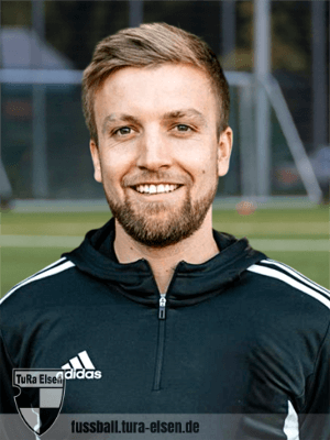 Trainer Fabian Wolf in einer schwarzen Adidas-Sportjacke mit weißem Logo und auf einem Fußballplatz