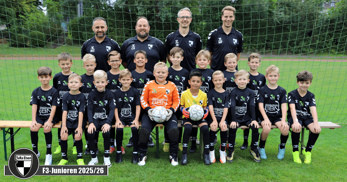 Mannschaftsfoto der F3-Junioren von TuRa Elsen für die Saison 2025/26. 11 Spieler in schwarzen Trikots und zwei Torwaret in Orange und Gelb, vier Trainer im Hintergrund.