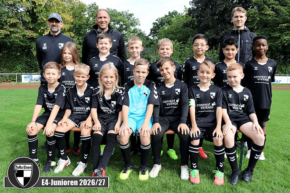 Gruppenfoto einer Jugendfußballmannschaft mit 14 Kindern in schwarzen Trikots und drei Trainern im Hintergrund auf einem Fußballfeld